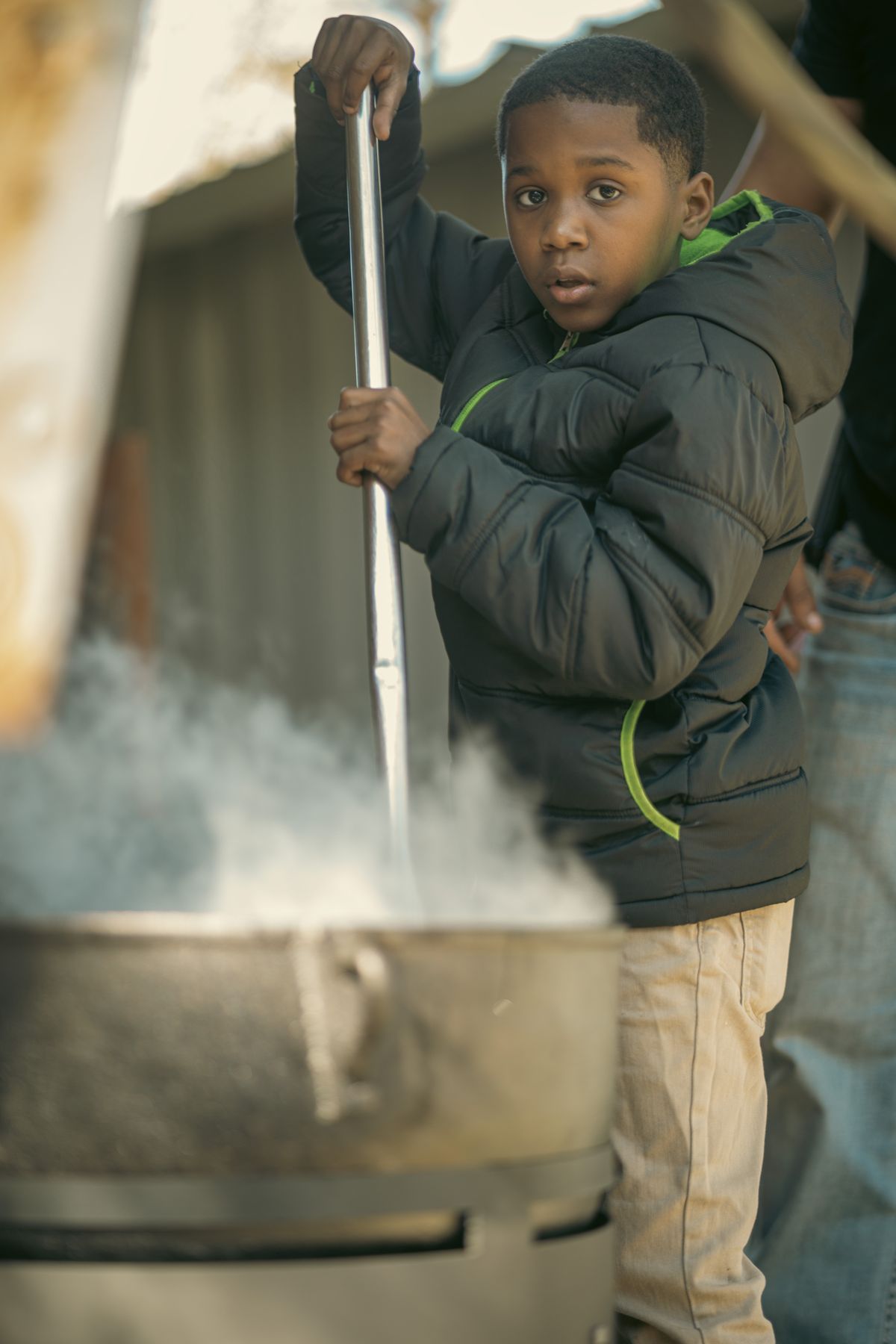 A young boy stirring cracklins